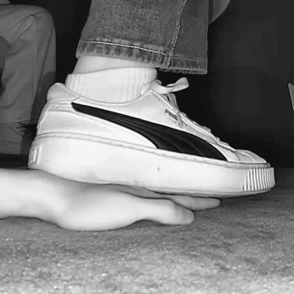 Woman candid hand trample with white socks and Puma sneakers in cinema